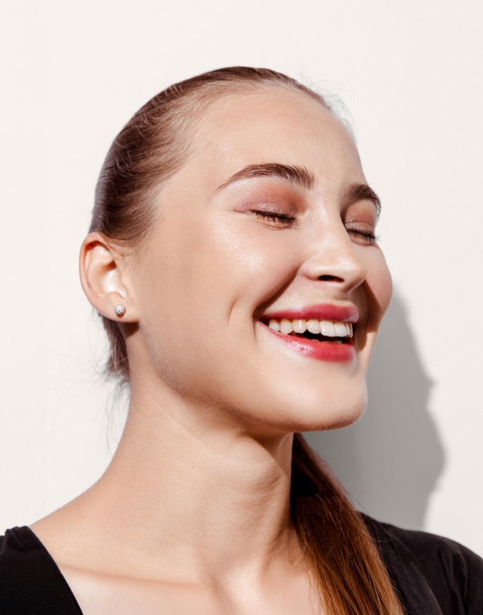 Mujer sonriente con el cabello recogido y los ojos cerrados