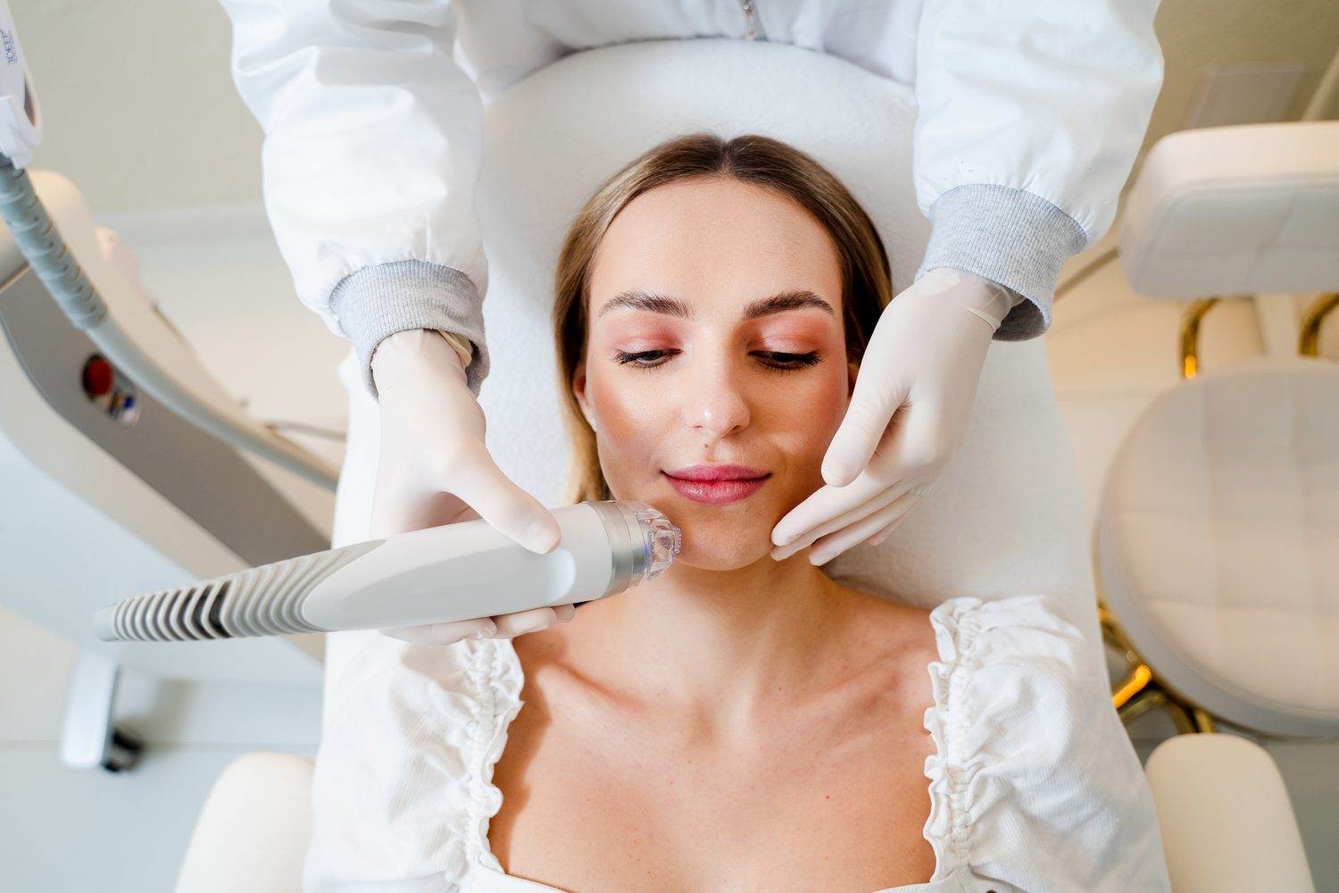 Woman receiving a facial skin treatment from a gloved practitioner