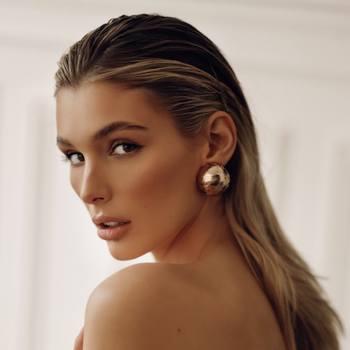 Mujer de cabello largo y rubio con un arete dorado