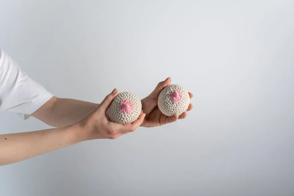 Hands holding crocheted breast models for breast cancer awareness.
